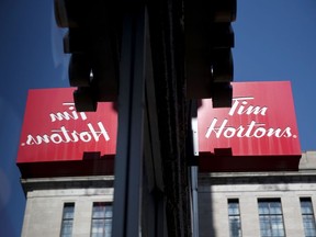 Tim Hortons Inc. signage is reflected in a window outside a store in Montreal on Monday, Aug. 20, 2018.