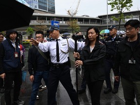 Police watch as a group of residents hold the first authorized protest and march in several years in Hong Kong.