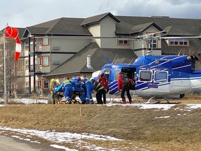 Rescue and medical personnel unload a patient from an RK Heliski helicopter at Invermere District Hospital during one of a half-a-dozen flights to bring people down the from the site of an avalanche that killed three and injured four people during a day of heli skiing in mountains above Invermere on March 1, 2023.