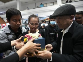Kamaery Promthep, center, Duangphet Phromthep's grandmother, holds his ashes at Mae Fah Luang airport in Chiang Rai province Thailand, Saturday, March 4, 2023.