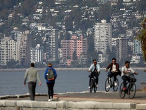 Cyclists ride on Stanley Park's seawall, across English Bay from West Vancouver condominiums, in Vancouver. Calls for more housing are dire as immigration numbers are set to increase