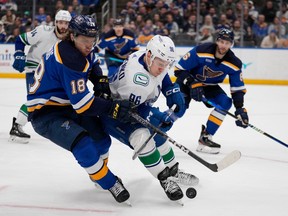 St. Louis Blues' Robert Thomas (18) and Vancouver Canucks' Andrei Kuzmenko (96) battle for a loose puck during the third period of an NHL hockey game Tuesday, March 28, 2023, in St. Louis.