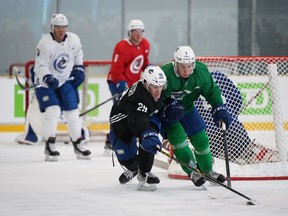 Vancouver Canucks' Kirill Kudryavtsev (29) reaches for the puck while being checked by William Lockwood (7) during the NHL hockey team's training camp in Whistler, B.C., Thursday, Sept. 22, 2022.