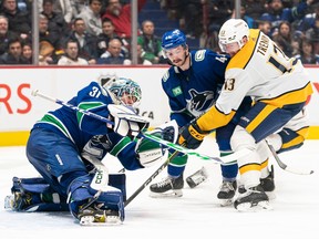 Vancouver Canucks goalie Arturs Silovs makes a glove save before Nashville Predators' Yakov Trenin can get his stick on the puck during the second period in Vancouver on Monday, March 6, 2023. Canucks' Kyle Burroughs tries to help defend on the play.