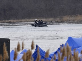 A police boat searches the area in Akwesasne, Que., Friday, March 31, 2023. Authorities in the Mohawk Territory of Akwesasne say one child is missing after the bodies of six migrants of Indian and Romanian descent were pulled from the river Thursday.