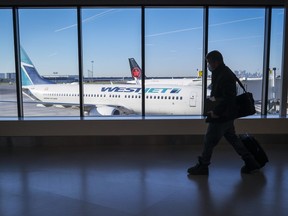 A passengers walks past WestJet and Air Canada planes at Calgary International Airport in Calgary, Alta., Wednesday, Aug. 31, 2022.