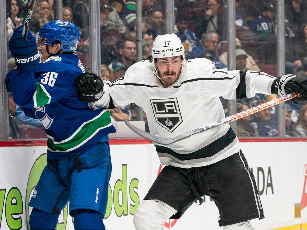Zack MacEwen of the Los Angeles Kings hits Akito Hirose of the Vancouver Canucks into the end boards during the second period at Rogers Arena on Sunday evening.