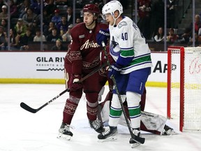 Canucks centre Elias Pettersson (right) gets jammed up with defenceman Michael Kesselring of the Arizona Coyotes during their March 16 game in Tempe, Ariz.