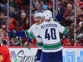 Ethan Bear #74 and Elias Pettersson #40 of the Vancouver Canucks celebrate a goal against the Chicago Blackhawks during the third period at United Center on March 26, 2023 in Chicago, Illinois.
