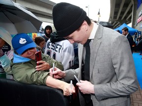 Akito Hirose of the Vancouver Canucks signs the arm of a fan before their NHL game against the Calgary Flames at Rogers Arena April 8, 2023.