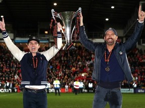 Rob McElhenney and Ryan Reynolds, Owners of Wrexham celebrate with the Vanarama National League trophy as Wrexham win the Vanarama National League and are promoted to the English Football League after victory in the Vanarama National League match between Wrexham and Boreham Wood at Racecourse Ground on April 22, 2023 in Wrexham, Wales.