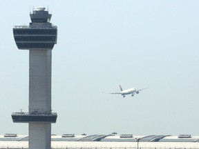 An aircraft flies past the control tower as it prepares to land at New York's John F Kennedy Airport, May 25, 2015. TREVOR COLLENS/AFP via Getty Images
