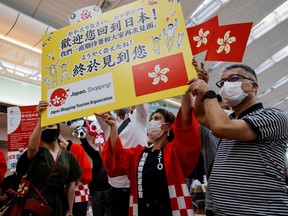 Members from Japan's shopping and tourism companies hold a placard reading 'Welcome back to Japan! We finally met you!' as they greet a group of tourists from Hong Kong upon their arrival at Haneda airport in Tokyo, Japan, June 26, 2022.