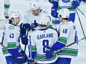 Vancouver Canucks right wing Conor Garland celebrates with defenceman Quinn Hughes and defenceman Cole McWard and centre Dakota Joshua after scoring the game winning goal in overtime against the Arizona Coyotes at Mullett Arena April 13, 2023.
