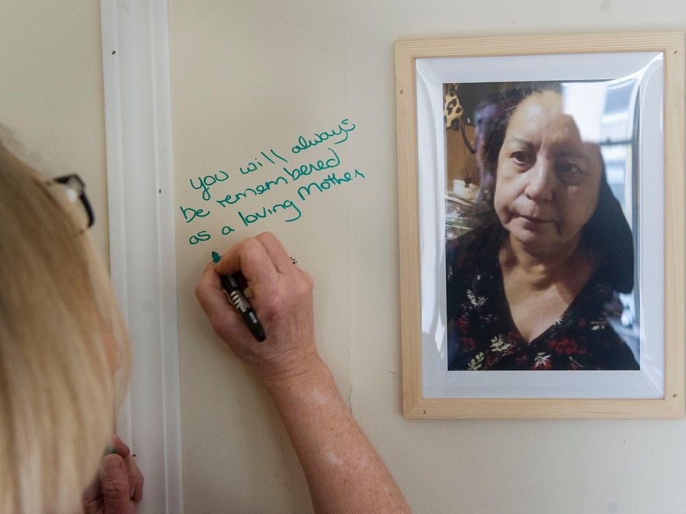 Tawow  assistant manager Justine Davies, a former tennant support worker at the Winters Hotel, writes a message on the memorial for fire victim Mary Garlow Tuesday. It has been one year since the Winters Hotel fire in Vancouver, BC, that killed two people and made dozens homeless. A memorial was set-up at Tawow hotel on Columbia Street Tuesday, April 11, 2023, where several former Winters residents now live. 
