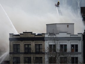 A firefighter on a ladder truck directs water on the fire burning at the Winters Hotel SRO on April 11, 2022.