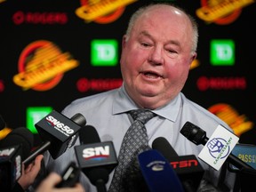 Bruce Boudreau responds to questions during a news conference while head coach of the Vancouver Canucks.