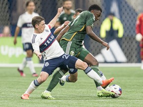Vancouver Whitecaps' Ryan Gauld, left, tries to take the ball away from Portland Timbers' Tega Ikoba during MLS action in Vancouver on April 8.