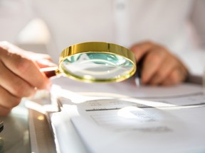 Businessman examining bill through magnifying glass in office