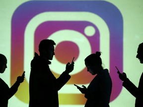 Silhouettes of mobile users are seen next to a screen projection of the Instagram logo in this picture illustration.