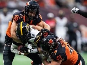 Hamilton Tiger-Cats quarterback Matthew Shiltz (18) is tackled by B.C. Lions’ Ben Hladik (46) and Tibo Debaillie (49) during the first half of CFL football game in Vancouver, on Thursday, July 21, 2022.