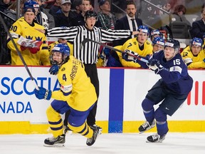Sweden’s Axel Sandin Pellikka and Finland’s Lenni Hameenaho chase a loose puck during the IIHF World Junior Hockey Championship tournament in January.