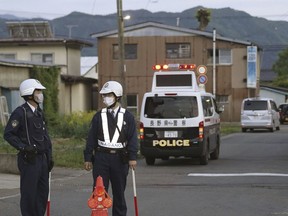 Police officers stand guard on a street leading to a building where a man is holed up in Nagano, Japan, Thursday, May 25, 2023.