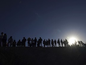 FILE - Migrants stand on the Mexican side of the U.S.-Mexico border, on the banks of the Rio Grande, in Ciudad Juarez, Mexico, March 29, 2023. About 50 migrants have been kidnapped by a gang in northern Mexico, the latest in a series of mass abductions, President Andres Manuel Lopez Obrador said Wednesday, May 17, 2023.