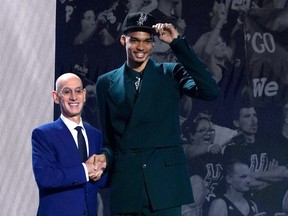 French basketball player Victor Wembanyama (R) shakes hands with NBA commissioner Adam Silver after being picked by the San Antonio Spurs during the NBA Draft at Barclays Center in New York city, on June 22, 2023.