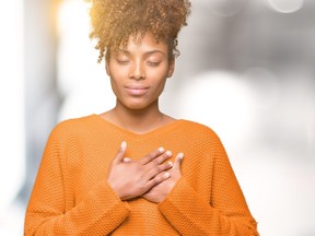Beautiful young african american woman over isolated background smiling with hands on chest with closed eyes and grateful gesture on face. Health concept.