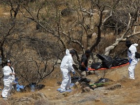 Forensic experts work with several bags of human remains extracted from the bottom of a ravine by a helicopter, which were abandoned at the Mirador Escondido community in Zapopan, Jalisco state, Mexico on May 31, 2023.