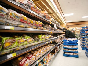 A worker restocks shelves in the bakery and bread aisle at a grocery store in Halifax. Canada Bread has settled allegations it took part in a price-fixing scheme that regulators contend began in 2001 and spanned at least 14 years.