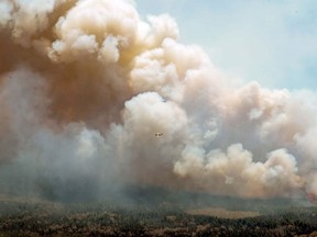 An aircraft (centre) disperses a mix of water and fire retardant over a fire near Barrington Lake in Shelburne County, N.S. in this Wednesday, May 31, 2023 handout photo. More than 300 firefighters from the United States and South Africa are heading to Canada in the coming days as the country battles an unprecedented wildfire season.