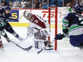 Seattle Thunderbirds forward Jared Davidson, left, and forward Dylan Guenther, right, try to get the puck past Peterborough Petes goalie Michael Simpson during first period semifinal CHL Memorial Cup hockey action in Kamloops, B.C., Friday, June 2, 2023.THE CANADIAN PRESS/Jeff McIntosh