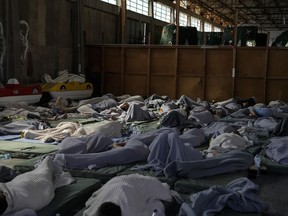 FILE - Survivors of a shipwreck sleep at a warehouse at the port in Kalamata town, about 240 kilometers (150 miles) southwest of Athens, June 14, 2023. Pakistani Prime Minister Shehbaz Sharif on Sunday, June 18 declared a national day of mourning for citizens who died when the fishing trawler packed with migrants they were in sank off the Greek coast.