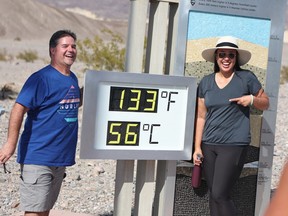 Clint Johnson, of Pleasant Hill, Calif., (left) and Melanie Anguay, of Las Vegas, stand next to a digital display of an unofficial heat reading at Furnace Creek Visitor Center during a heat wave in Death Valley National Park in Death Valley, California, on July 16, 2023.