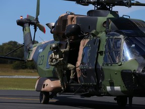 In this file photo taken on March 28, 2021, a member of the 5th Aviation Regiment, Townsville is seen aboard a MRH-90 Taipan arriving at Taree Airport as part of flood recovery and assist duties in Taree, Australia.