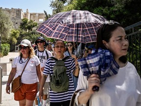 Visitors leave the Acropolis archeological site in Athens on July 14, 2023.