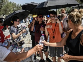 Hellenic Red Cross workers distribute bottles of water to visitors outside the Acropolis in Athens on July 13, 2023, as Greece hits high temperatures.