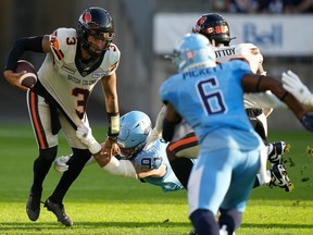 Toronto Argonauts defensive lineman Thomas Costigan (97) stops BC Lions quarterback Vernon Adams Jr. (3) during first half CFL action in Toronto on Monday, July 3, 2023.