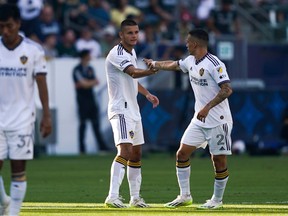 Los Angeles Galaxy defender Lucas Calegari (2) high fives teammate Dejan Joveljic after a goal by teammate Riqui Puig during the first half of an MLS soccer match against the Vancouver Whitecaps, Sunday, July 30, 2023, in Carson, Calif.