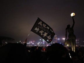 A protester holds a flag reading "Liberate Hong Kong, the Revolution of Our Times" during a demonstration in Hong Kong, Tuesday, Dec. 31, 2019.