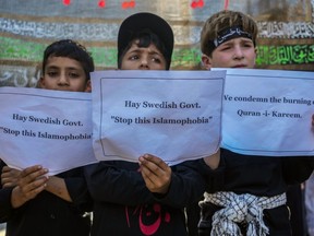 Kashmiri children hold placards as they participate in a gathering condemning the desecration of the Quran in Sweden, during a Muharram procession in Srinagar, Indian controlled Kashmir, Wednesday, July 26, 2023.