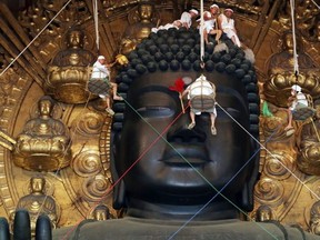 FILE: Buddhist monks and volunteers clean the 15-metre-tall great Buddha statue during the annual Ominugui ceremony at Todaiji Temple in Japan's ancient capital Nara, western Japan on August 7, 2014.