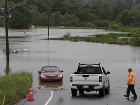 A man surveys damage at the edge of floodwater as vehicles are seen abandoned in water following a major rain event in Halifax on Saturday, July 22, 2023.