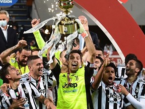 Former Juventus goalkeeper Gianluigi Buffon holds the winner's trophy amd celebrates winning the Coppa Italia in 2021.