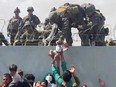 A baby is handed over the perimeter wall of the Kabul airport to soldiers for evacuation on Aug. 19, 2021, amid chaos following the American withdrawal from Afghanistan and the return of Taliban rule.