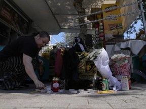 A woman lights a candle, on the location where a 29-year-old Greek fan has died after overnight clashes between rival supporters in Nea Philadelphia suburb, in Athens, Greece, Tuesday, Aug. 8, 2023.