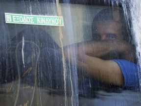 A soccer fan sits inside a police bus upon his departure from the Athens Police Headquarters, Greece, Wednesday, Aug. 9, 2023.