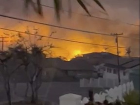 This image from video provided by Robert Arconado shows fires in the background seen from his home on the Hawaiian island of Maui on Aug. 8, 2023. Videos showing downed power lines apparently sparking some of the early blazes in the Maui wildfires have become key evidence in the search for a cause.